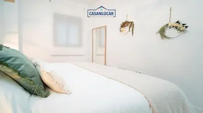 a bedroom with a white bed with a sign on the wall at Apartamento Diego Benitez in Sanlúcar de Barrameda