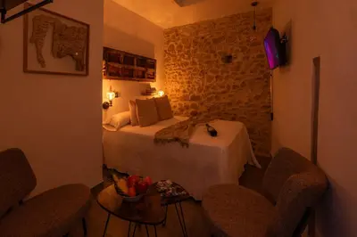 a bedroom with a bed with two chairs and a table at Alojamientos Plaza de España in Medina Sidonia