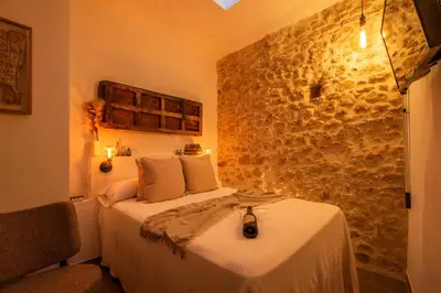a bedroom with a bed and a stone wall at Alojamientos Plaza de España in Medina Sidonia
