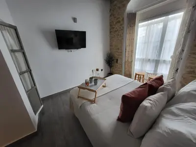 a bedroom with a white bed and a couch at Alojamientos Plaza de España in Medina Sidonia