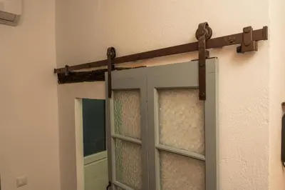 a sliding glass door with a wooden handle on a wall at Alojamientos Plaza de España in Medina Sidonia