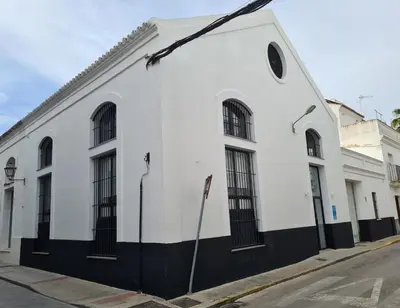 a white building with black windows on a street at Bodega Mar - Manzanilla in Sanlúcar de Barrameda