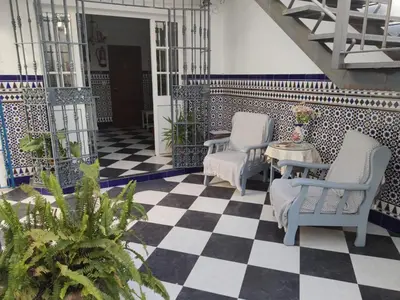 a patio with two chairs and a table on a checkered floor at Hostal Sevillana Costa in Chipiona