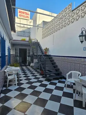 a black and white checkered floor with stairs and tables at Hostal Sevillana Costa in Chipiona