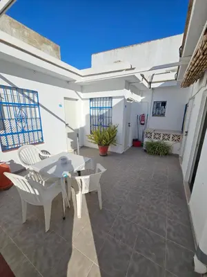 a patio with white furniture and a table and chairs at Hostal Sevillana Costa in Chipiona