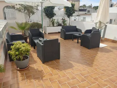 a patio with chairs and tables and an umbrella at ALOJAMIENTO La CAPILLITA HABITACION CON BAÑO in Sanlúcar de Barrameda
