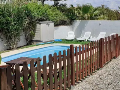 a fence next to a pool with chairs and a table at Chalet Zorollo con piscina in Conil de la Frontera