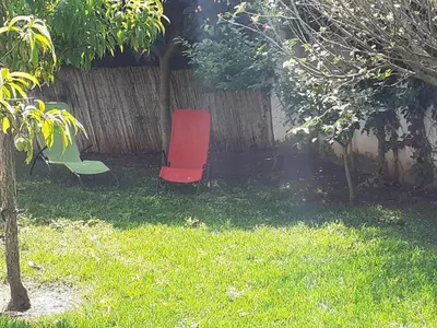 a red chair sitting in a yard next to a fence at Chalet Zorollo con piscina in Conil de la Frontera