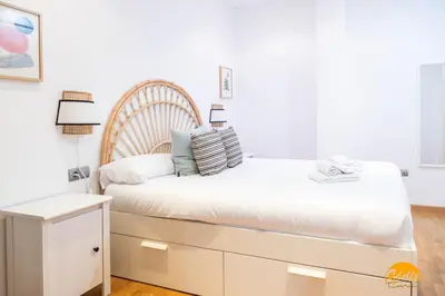 a bedroom with a white bed with a wooden headboard at Rincon del Mar - FREE PARKING by Cadiz Time in Cádiz