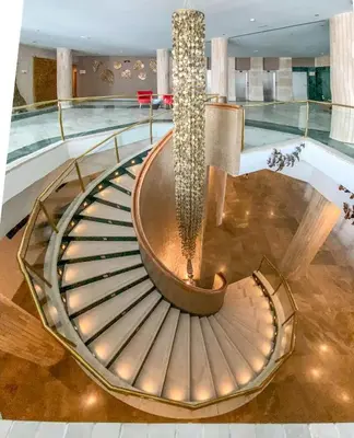 a spiral staircase in a lobby with a chandelier at Cádiz Bahía by QHotels in Cádiz