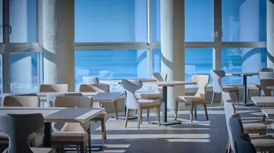 a room with tables and chairs and windows at Cádiz Bahía by QHotels in Cádiz