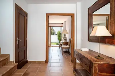 a hallway with a mirror and a table with a lamp at Casa Poniente en playa Fuente del Gallo in Conil de la Frontera