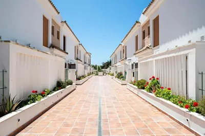 an empty street with flowers and buildings at Casa Poniente en playa Fuente del Gallo in Conil de la Frontera