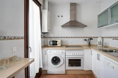 a kitchen with a washing machine and a microwave at Casa Poniente en playa Fuente del Gallo in Conil de la Frontera