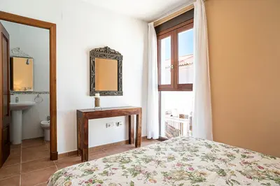 a bedroom with a bed and a mirror and a window at Casa Poniente en playa Fuente del Gallo in Conil de la Frontera