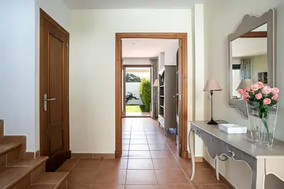a hallway with a mirror and a vase of flowers on a counter at Casa Levante en playa Fuente del Gallo in Conil de la Frontera