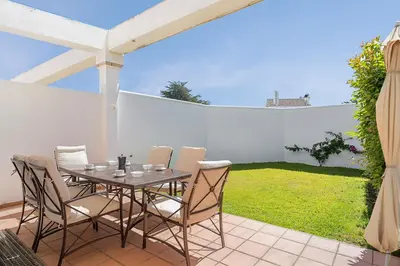 a table and chairs on a patio with a garden at Casa Levante en playa Fuente del Gallo in Conil de la Frontera