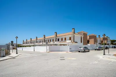 a large building with cars parked in a parking lot at Casa Levante en playa Fuente del Gallo in Conil de la Frontera