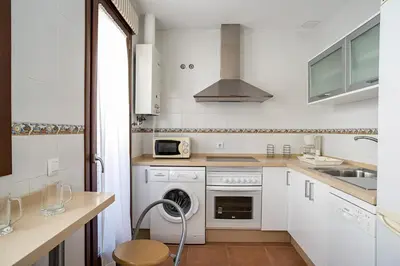 a kitchen with white cabinets and a washer at Casa Levante en playa Fuente del Gallo in Conil de la Frontera