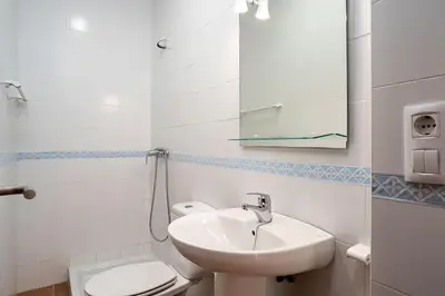 a bathroom with a sink and a toilet and a mirror at Casa Levante en playa Fuente del Gallo in Conil de la Frontera