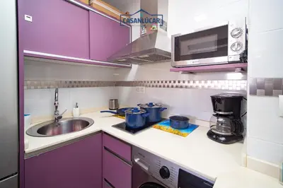 a small kitchen with purple cabinets and a sink at Apartamento Aránzazu playa in Sanlúcar de Barrameda
