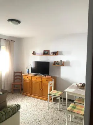 a living room with a television and a table with chairs at Casa en primera línea de playa in Rota