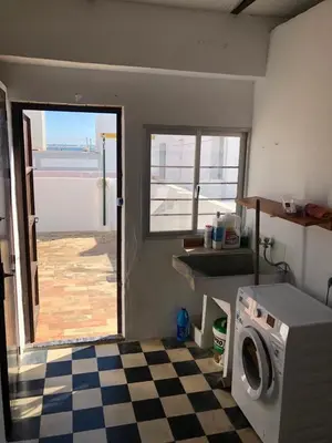 a kitchen with a washer and a checkered floor at Casa en primera línea de playa in Rota