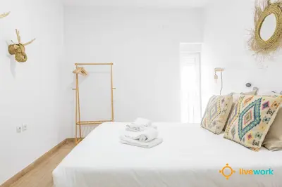 a white bedroom with a bed with towels on it at Casa del Pescador by LiveWork in Cádiz