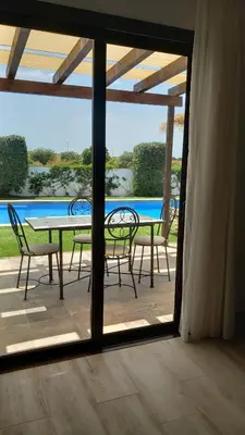 a table and chairs on a patio with a view of a pool at Alojamiento El Drago - Sólo Familias y Parejas in Conil de la Frontera