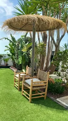 two chairs under an umbrella on the grass at Alojamiento El Drago - Sólo Familias y Parejas in Conil de la Frontera