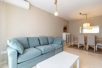 a living room with a blue couch and a table at Allo Apartments Europa I Parking Piscina Padel 3 Habitaciones in Jerez de la Frontera