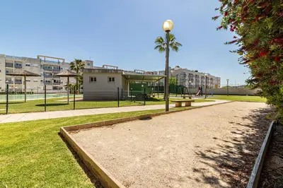 a park with a bench and palm trees and buildings at Allo Apartments Europa I Parking Piscina Padel 3 Habitaciones in Jerez de la Frontera