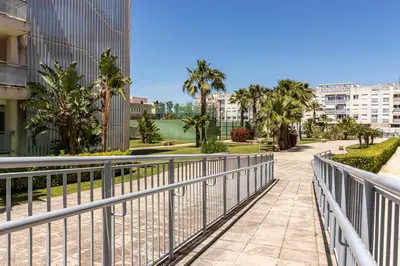 a walkway through a park with palm trees and buildings at Allo Apartments Europa I Parking Piscina Padel 3 Habitaciones in Jerez de la Frontera