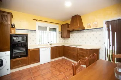 a kitchen with wooden cabinets and a sink and a stove at Villa las Raices in Sanlúcar de Barrameda