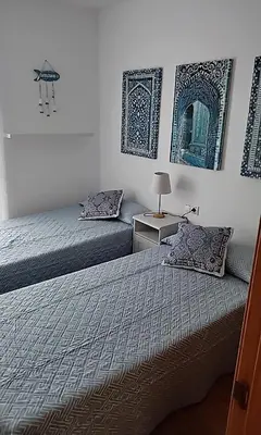 a bedroom with two beds and a table and a mirror at Casa Lua in Conil de la Frontera