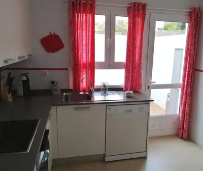 a kitchen with a sink and a window with red curtains at Casa Lua in Conil de la Frontera