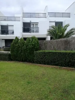 a white building with a fence in front of a yard at Casa Lua in Conil de la Frontera