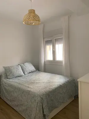 a white bedroom with a bed and a window at Playa Apartamento Lidia in Cádiz