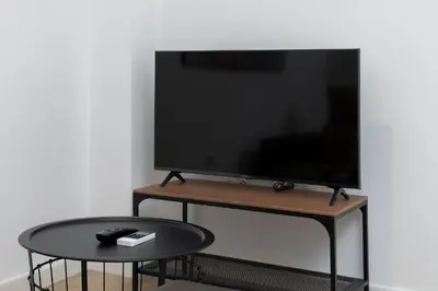 a flat screen tv on a stand with a table at Estudio Las Navas in Cádiz