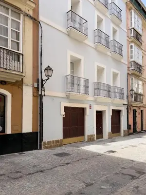 an empty street in front of a white building at El Rincón de Fabio Little Apartments in Cádiz