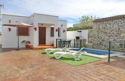 a patio with two white chairs and a pool at Villa Ana in Conil de la Frontera