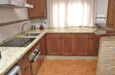 a kitchen with wooden cabinets and a sink and a window at Villa Ana in Conil de la Frontera