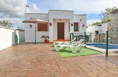 a patio with two white chairs and an umbrella at Villa Ana in Conil de la Frontera