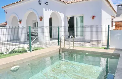 a swimming pool in front of a white house at Villa Alonso in Conil de la Frontera