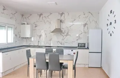 a white kitchen with a table and chairs at Villa Alonso in Conil de la Frontera