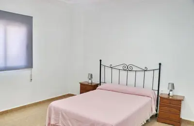 a bedroom with a bed with pink sheets and a window at Villa Alonso in Conil de la Frontera