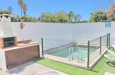 a swimming pool in a fence with a grill at Villa Alonso in Conil de la Frontera