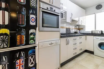 a kitchen with white cabinets and a microwave at Mirador del Sur Penthouse & SunSet - Free Parking in Jerez de la Frontera