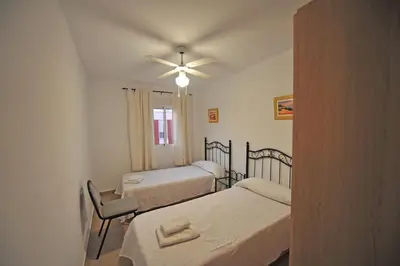 a room with two beds and a ceiling fan at Laguna 3 dormitorios Acogedor in Cádiz