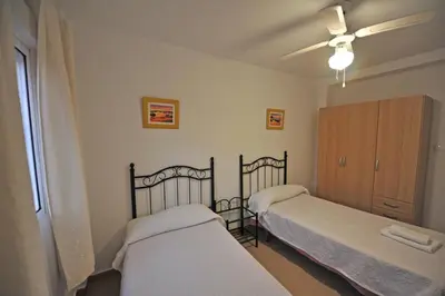 a bedroom with two beds and a ceiling fan at Laguna 3 dormitorios Acogedor in Cádiz